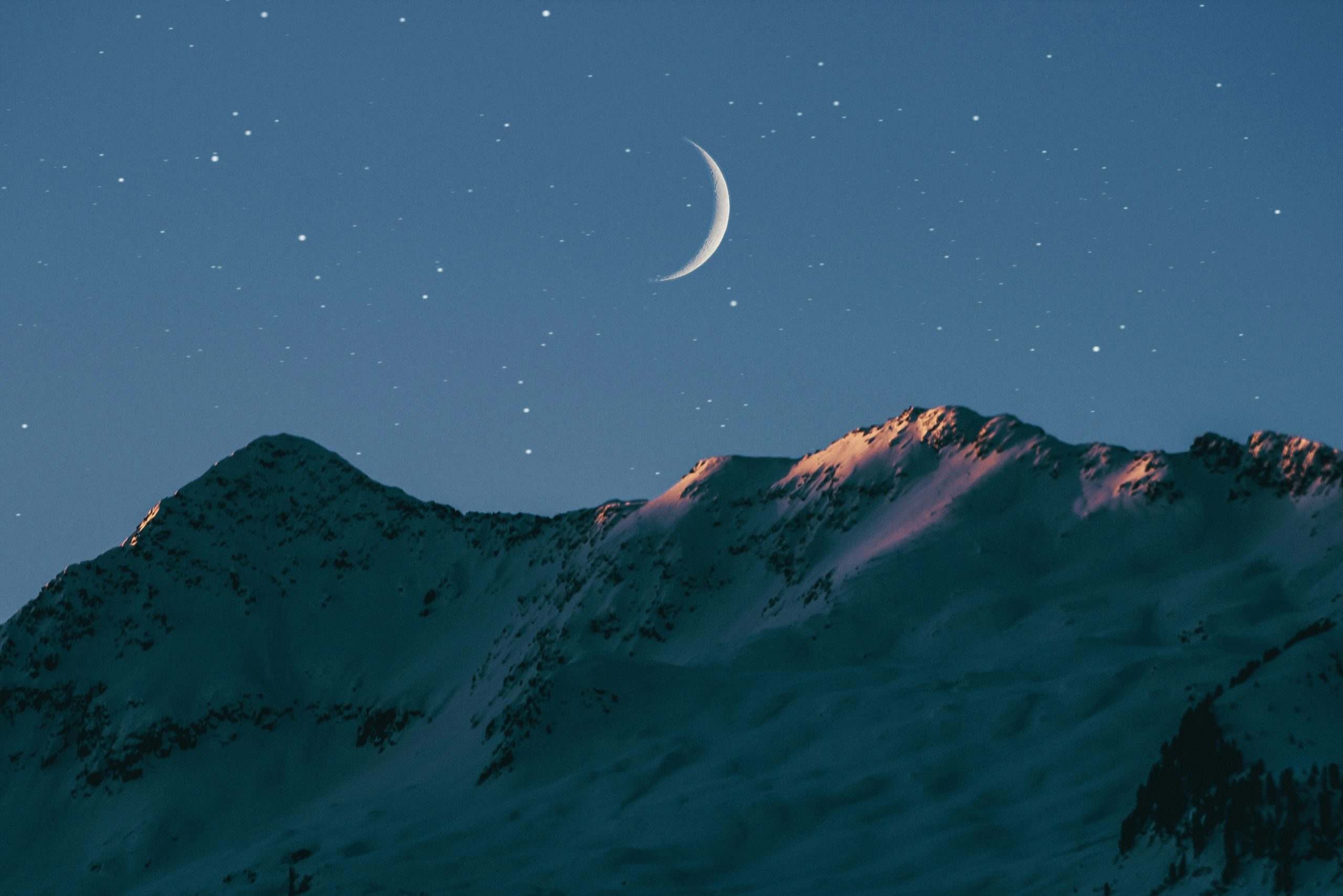crescent moon over mountains